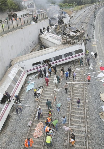 24日，救援人員在西班牙列車脫軌現場。一節(jié)車廂被強大的慣性拋上鐵道邊的高臺。