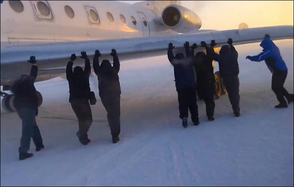 伊加爾市一架客機起飛前被凍在了跑道上。飛機上的乘客不得不下來推飛機。