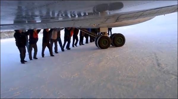 　伊加爾市一架客機起飛前被凍在了跑道上。飛機上的乘客不得不下來推飛機。