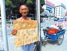 老人舉著牌子在路邊等候失主。京華時(shí)報(bào)記者譚青攝