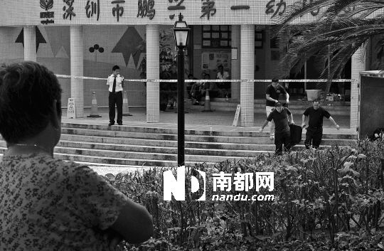 →7月19日，鵬興花園第一幼兒園門前，民警在現(xiàn)場進行完勘查取證后，園長和保安的尸體被運走。南都記者 徐文閣 攝