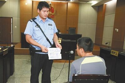 昨日庭審中，法警向趙某出示其扎完車(chē)胎后所留辱罵公司的紙條。通訊員 李秀文 攝