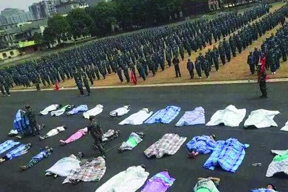 20多名女生躺在瀝青跑道上，身上嚴嚴實實地裹著棉被，接受太陽的照曬。
