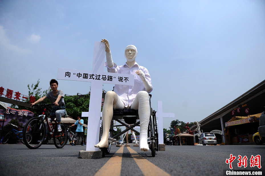 4月16日，重慶市洋人街上擺放著兩個(gè)受了傷的塑料人像“模特”，旁邊十字架上寫著向“中國式過馬路”說不