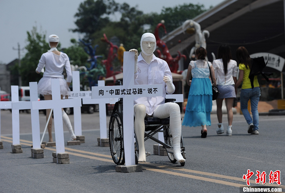 4月16日，重慶市洋人街上擺放著兩個(gè)受了傷的塑料人像“模特”，旁邊十字架上寫著向“中國式過馬路”說不