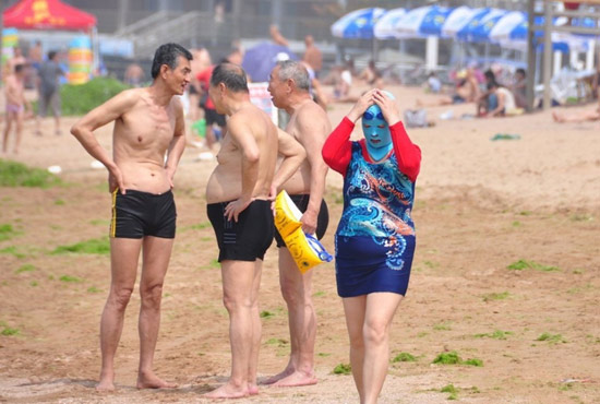 2013年7月3日，山東青島青島高溫來襲，“青島大媽”不懼滸苔，戴著“強(qiáng)盜面具”出現(xiàn)在海水浴場消暑降