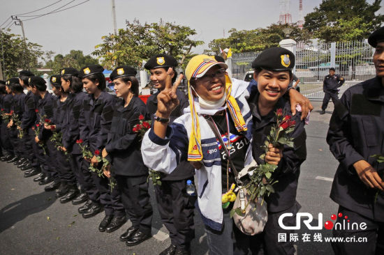 2013年12月03日,曼谷總理府與曼谷警署允許反政府示威民眾進入,雙方進入暫時“停戰(zhàn)”狀態(tài)迎接泰王生日。曼谷警察總署,女警們手持鮮花送給反政府示威民眾。圖片來源:Manish Swarup/東方IC