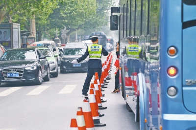 省人民醫(yī)院南門的路中間擺放反光錐，交警示意由西向東車輛從前方繞行。