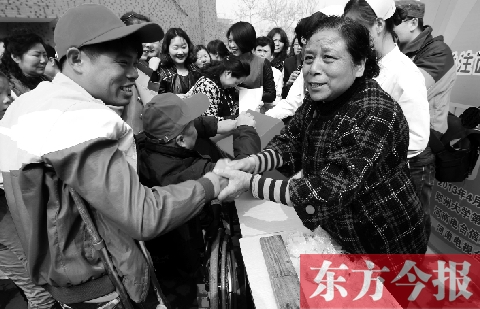 昨日，鄭大四附院的大樓前，“面人鄭”鄭玉芬（右）向前來捐款的殘疾人表示感謝