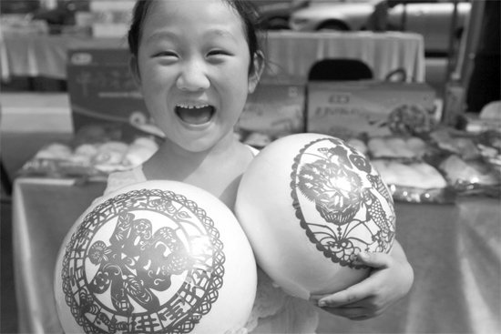 在2013河南食品安全宣傳周活動(dòng)現(xiàn)場(chǎng)，一個(gè)小女孩抱著參展的特色大饅頭樂(lè)開(kāi)了花