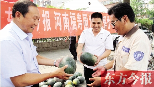 河南福壽園區(qū)域總經(jīng)理吳正宗（左一）、東方今報發(fā)行中心副總監(jiān)王路喜（中）在街頭給市民送瓜