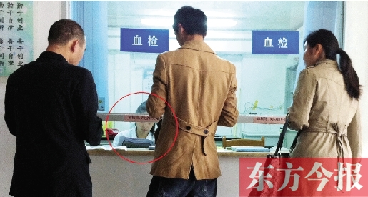 昨日，鄭州市二七區(qū)疾控中心辦證大廳，血檢窗口內(nèi)一名女工作人員，邊接受辦證者咨詢邊看報紙