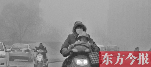 12月8日，鄭州市未來路上，一位市民帶著孩子在霧中騎行