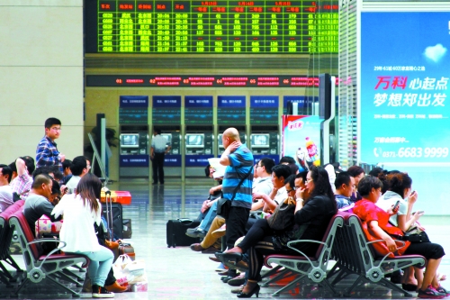 候車大廳溫度很高，一名乘客一手扇風、一手擦汗
