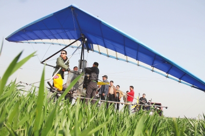 　　4月12日，在武陟縣北郭鄉(xiāng)韓余村，一架三角翼動(dòng)力滑翔機(jī)在對(duì)小麥進(jìn)行農(nóng)藥噴灑作業(yè)。為提升農(nóng)業(yè)生產(chǎn)的
