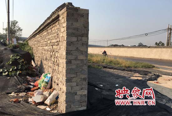 一墻之隔，一邊是道路，一邊是垃圾和荒草，市民質疑其為遮羞墻。