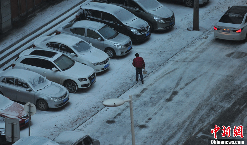 11月18日，行人在沈陽街頭的積雪中穿行。