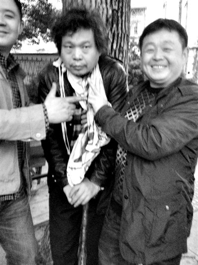 兩名接訪人員與患有癌癥的訪民段新德合影時，面帶笑容擺出勝利的手勢。
