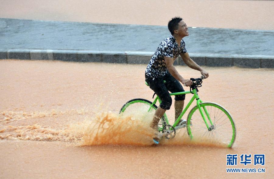 5月11日，一名行人在深圳街頭冒雨騎行。