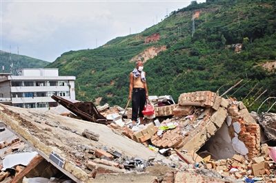 8月9日,龍頭山鎮(zhèn),一位老者在自家房屋廢墟上尋找家當(dāng)。