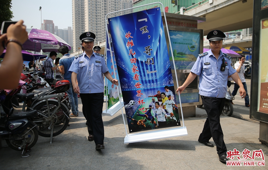 7月2日上午，鄭州市紫荊山地鐵站出入口，執(zhí)法人員抬著寫有勸導(dǎo)語的宣傳板，前往占道經(jīng)營攤位“圍觀執(zhí)法”