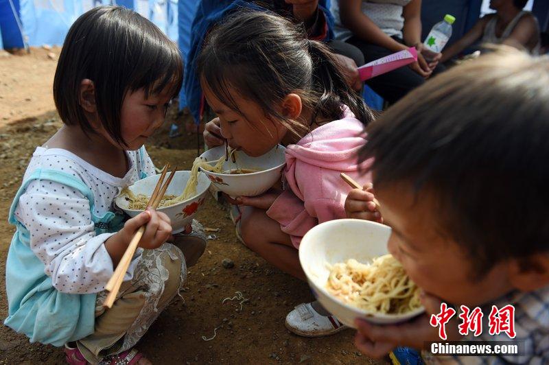 2014年8月6日，云南魯?shù)辇堫^山災(zāi)區(qū)，兒童在帳篷外吃飯。