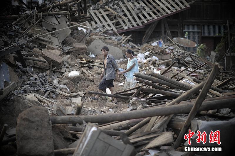 2014年8月5日，云南昭通龍頭山鎮(zhèn)老街，一對夫妻從居住房屋的廢墟中走過。