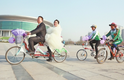 氣球和鮮花裝點(diǎn)的雙人自行車，新郎郝幸福載著美麗新娘回家。