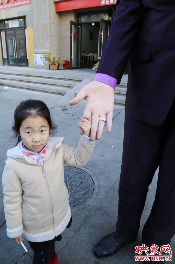 巨人“張歡”牽著一名漂亮的小女孩，兩人的手大小對比非常明顯。
