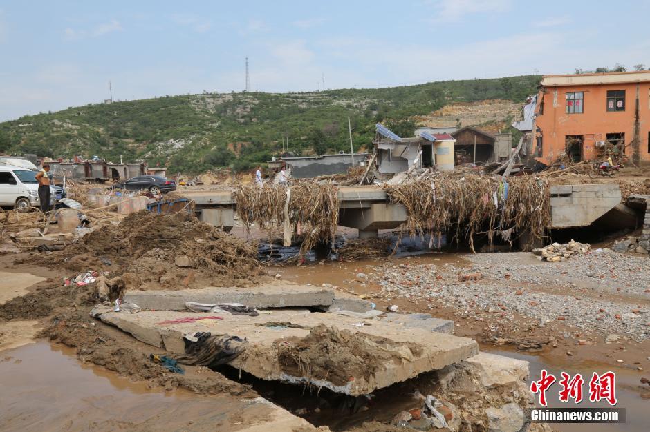 圖為洪水過(guò)后，坍塌的橋梁上遺落大量雜草。