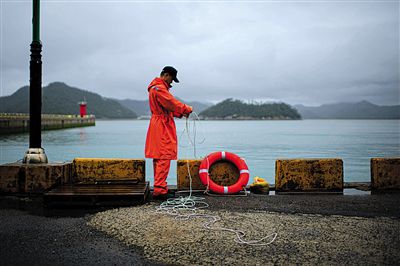 7月6日，韓國珍島，一名海岸警察在港口系救生圈。4月，客輪在珍島近海發(fā)生沉船事故后，仍有11人下落不明。