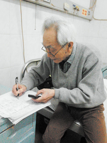 杜修源老人埋頭寫著特殊的“日記”。 李卓 攝