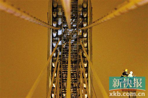截至今日零時(shí)，男子仍未有下橋舉動(dòng)。圖為公安和消防人員乘消防云梯在高空上和男子交談。