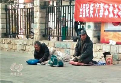 工人體育場北路，兩位乞討者路邊乞討，并輪流扮成“病人”（躺地者）。 央視截圖