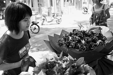 鄭州市農(nóng)業(yè)路一家花店擺放的玫瑰花吸引著一位過往女孩。